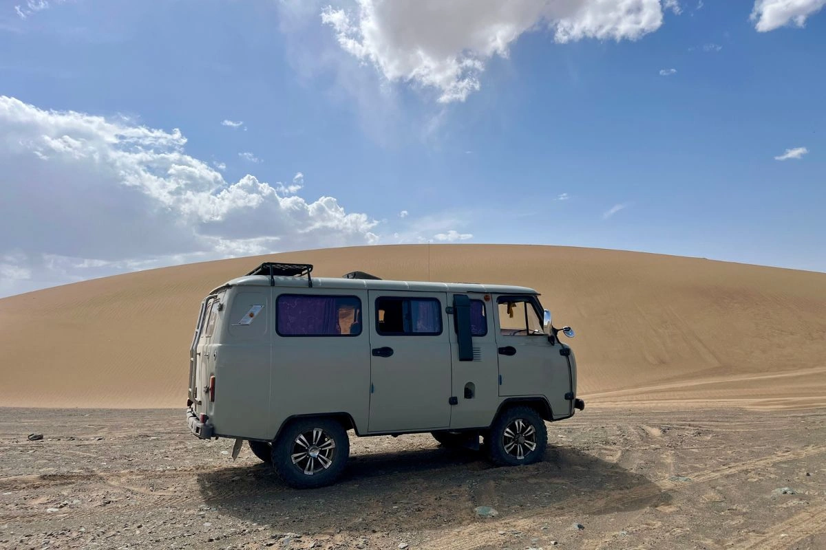 Minibus tout-terrain sur une piste au pied des dunes du Gobi